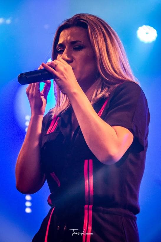 Alexandra Mussard au micro sur scène, lumière bleue
